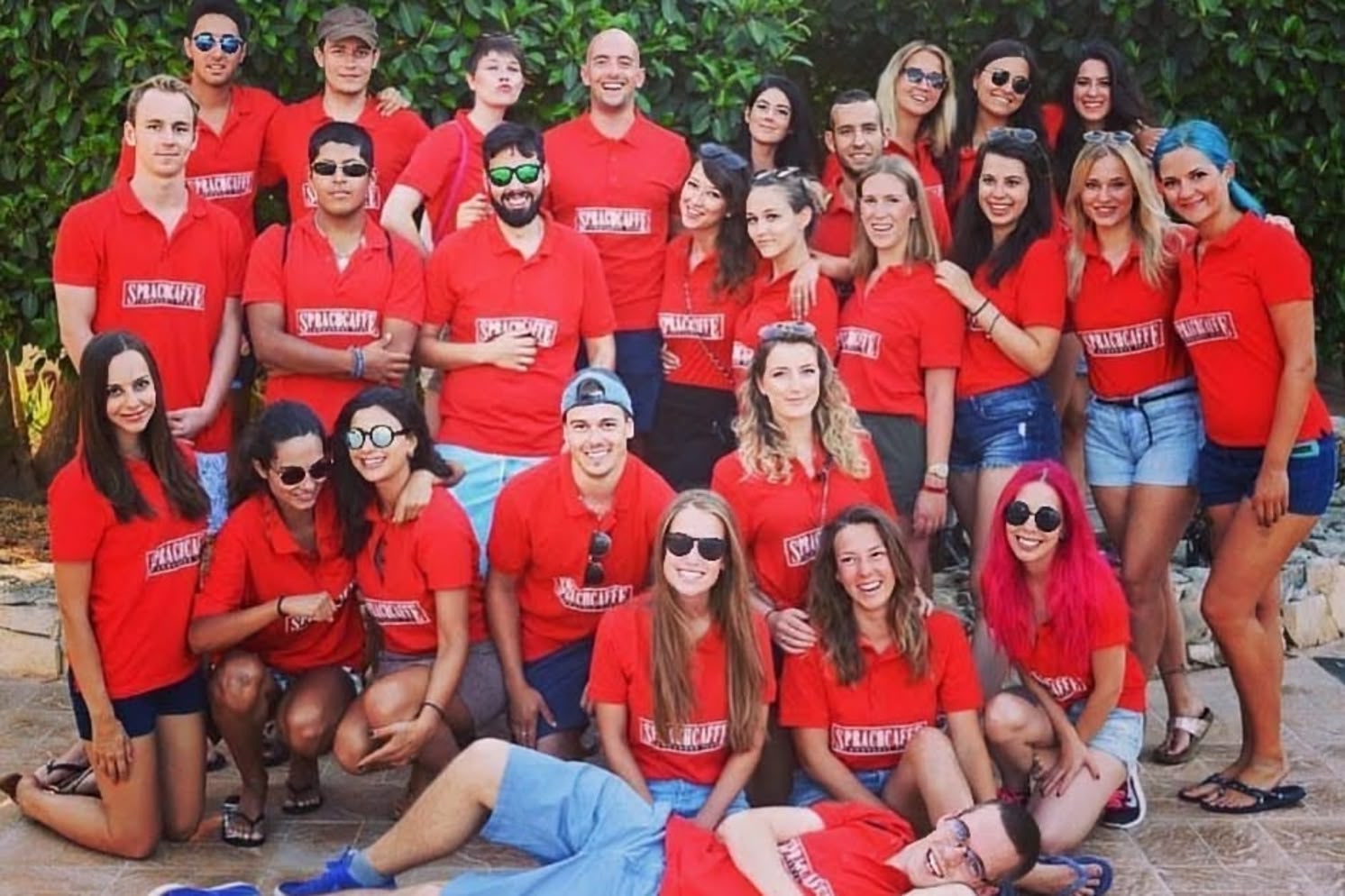 Group of Sprachcaffe Malta teamers posing together outdoors, all wearing matching red Sprachcaffe shirts.
